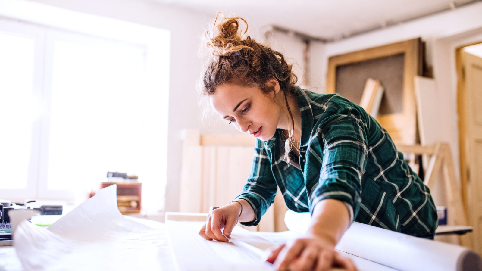 Small business of a young woman. Beautiful young woman worker in a workroom, measuring wood.